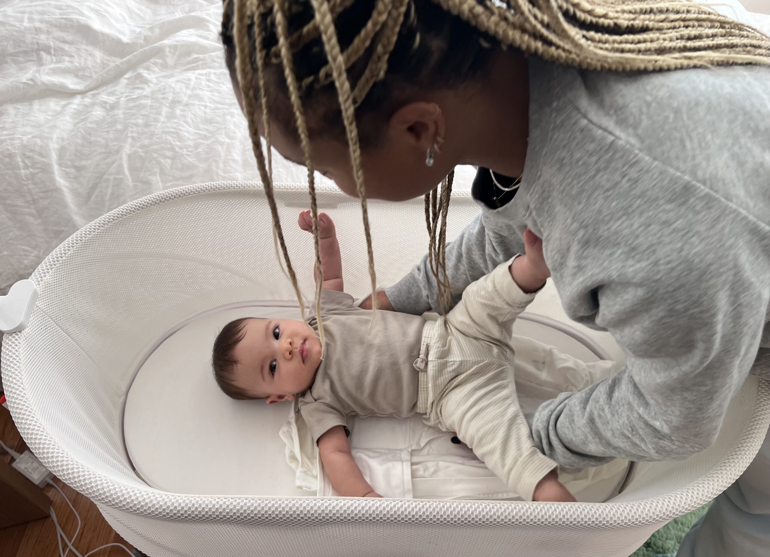 A mom puts her baby in SNOO Smart Bassinet